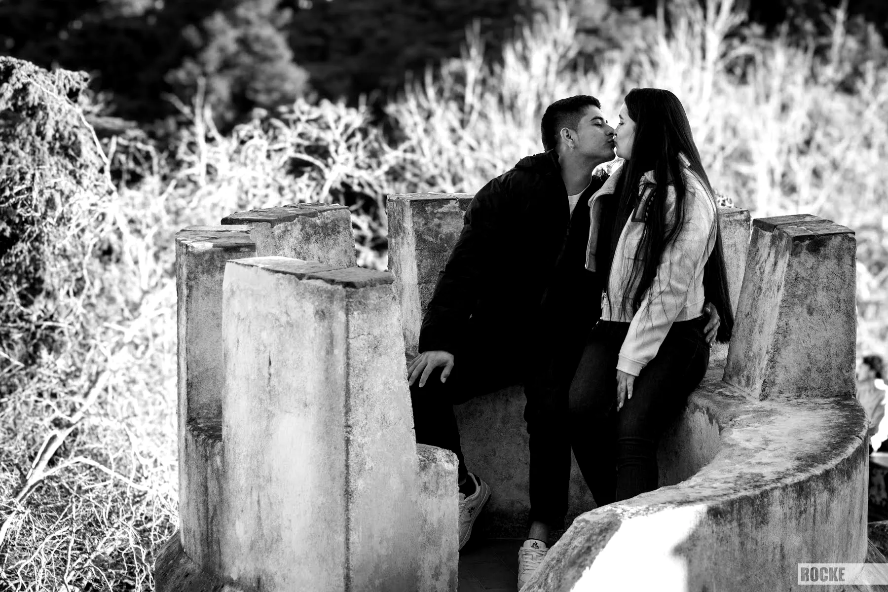 Black-and-white El Beso photograph of a couple kissing at an overlook in Lisbon, Portugal.